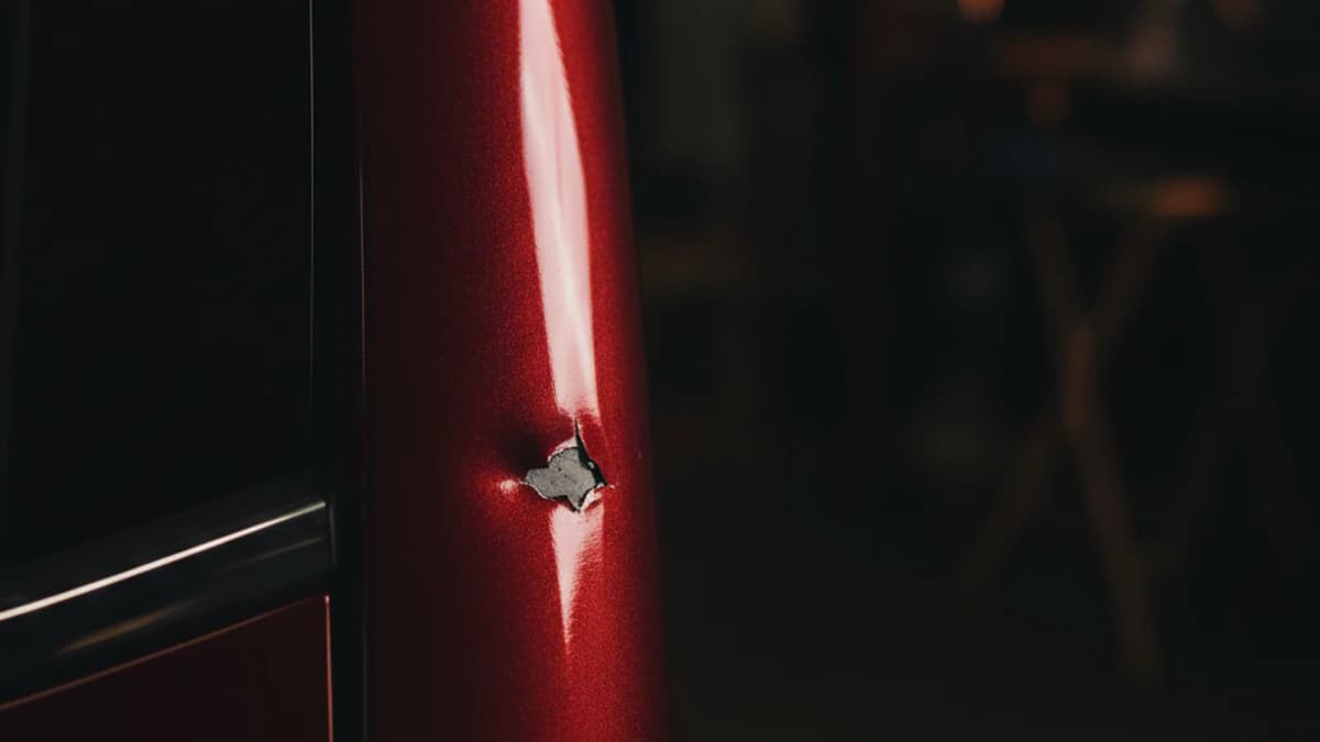 Close-up of a Skoda Kodiaq B-pillar in Velvet Red Premium Metallic with a small dent and paint chip